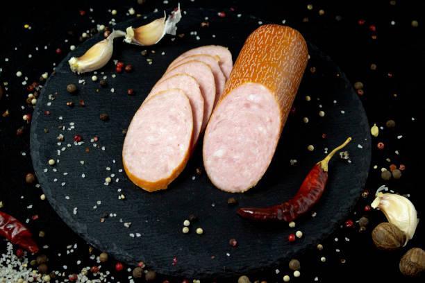 istock Appetizing sausage sliced on a slate board on a black background with spices and chilli, selective artistic focus 1292537642