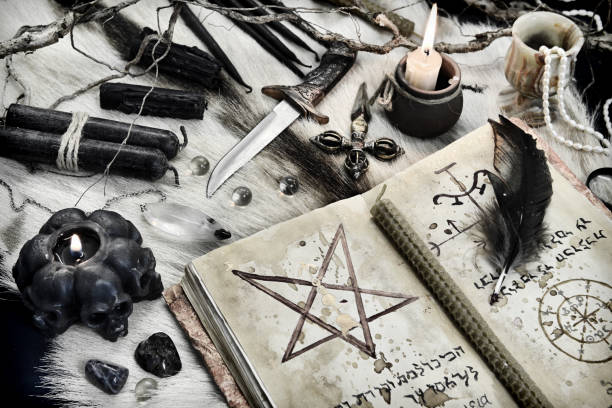 istock Styled still life with black magic grimoire book, burning candles and ritual objects on witch table 1292539363