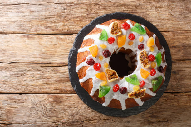 Freshly baked cake with raisins, dried apricots, dried cherries, kiwi and cranberries and icing close-up on a board. horizontal top view Freshly baked cake with raisins, dried apricots, dried cherries, kiwi and cranberries and icing close-up on a board on the table. horizontal top view from above fruitcake stock pictures, royalty-free photos & images