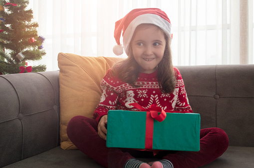 Happy smiling child girl with Christmas present at home
