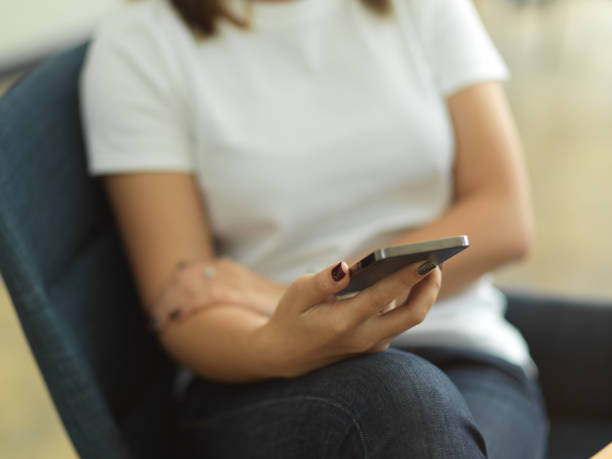 istock Female hand holding smartphone while relaxed sitting in office room 1292542502