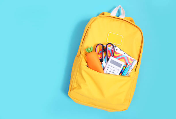 istock Yellow backpack with school supplies on blue background empty copy space.School accessories objects set.Back to school. 1292542721