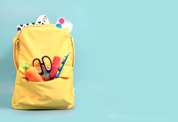 istock Yellow backpack with accessories, school supplies in schoolbag on empty space green background.Knapsack with education objects. 1292542722