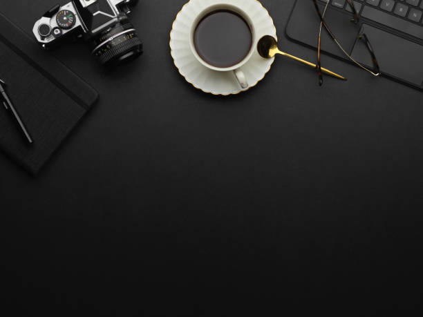 istock Top view of copy space on black table with coffee cup, camera and supplies 1292545069