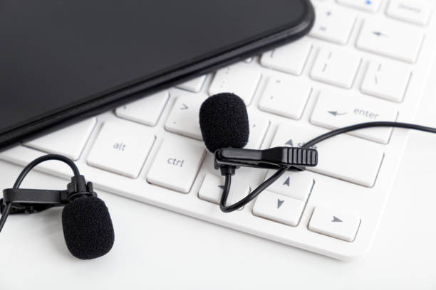 2 small microphones lie on a white keyboard and with a phone. - blog internet podcast computer keyboard imagens e fotografias de stock