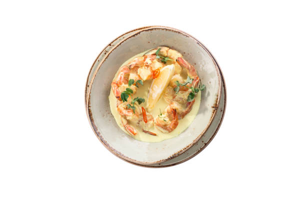 shrimp saute with cream sauce and lemon isolated on white background top view