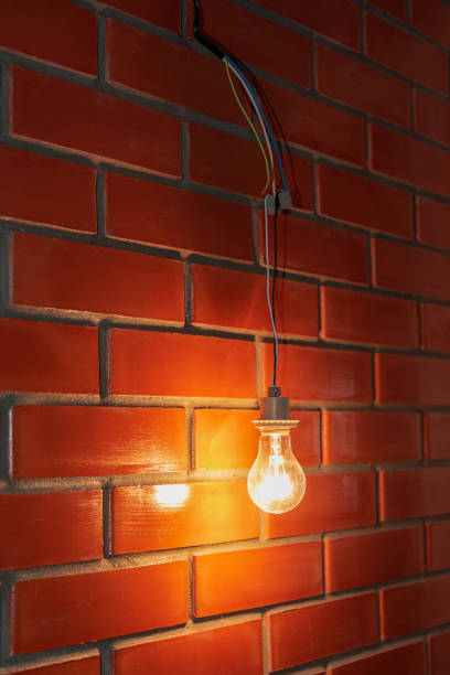 istock incandescent lamp hanging from wires on a brick wall 1292549063