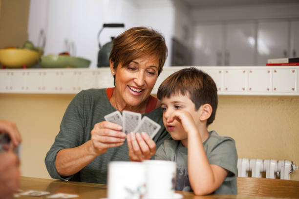 istock Grandson and grandmother talking with complicity while she plays cards. 1292549124