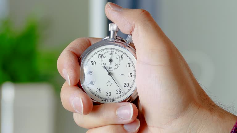 The man presses the start button of a vintage stopwatch he is holding.