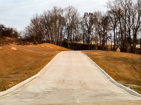 You are looking down a brand new concrete driveway. Either side of the driveway has been excavated and is awaiting landscaping. \