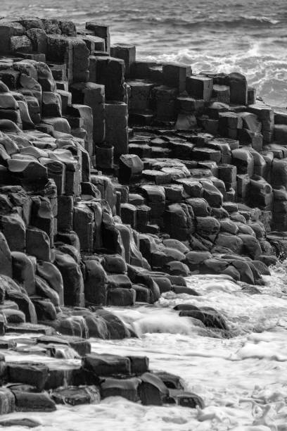 Basalt Black and white image of basalt rocks and a rough sea. northern ireland photos stock pictures, royalty-free photos & images