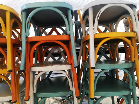 stack of wooden colorful chairs background, concept closed restaurant, \neconomic difficulties for catering