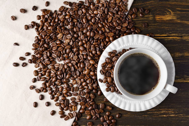istock Hot coffee and coffee beans on wooden background 1292563422