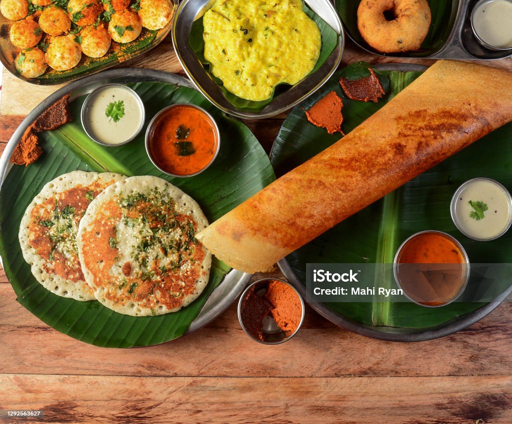 Assorted South indian breakfast foods on wooden background. Ghee dosa, uttappam,medhu vada,pongal,podi idly and chutney.. Dishes and appetizers of indian cuisine South Stock Photo