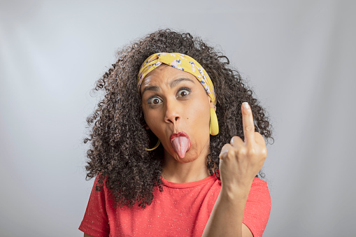 Brazilian young woman with curly hair making obscene gesture with middle finger