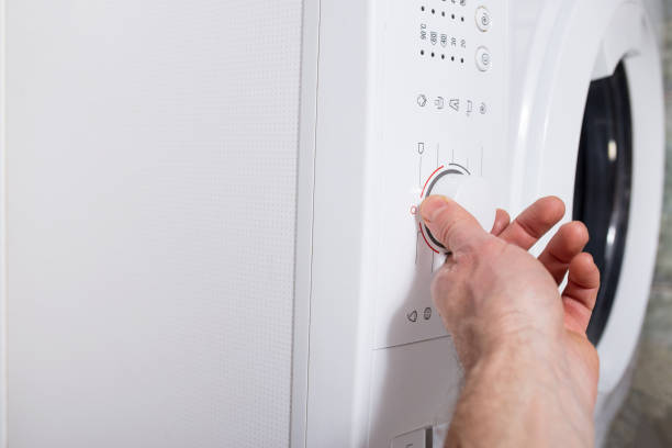 istock Man turn on washer. Turn on washing mashine. Family routine 1292567120