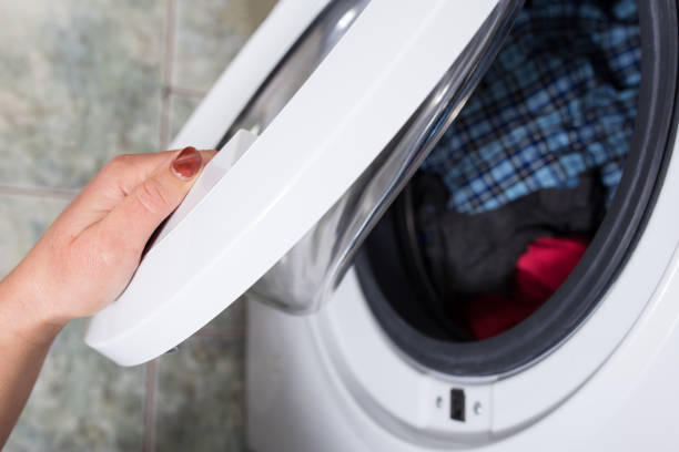 istock Laundry day. Woman in laundry. Load a washing machine 1292567124
