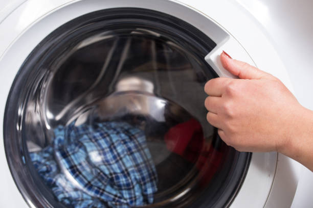istock Close a washing machine door. Hand opening washer 1292567182
