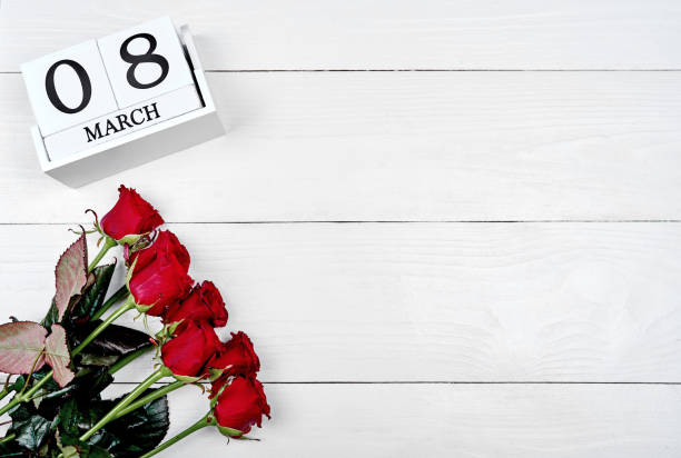 istock Beautiful red roses with cube calendar on white wooden background, copy space for text. Save the date white block calendar for International Women's Day, March 8. Greeting card. Top view, flat lay 1292568252