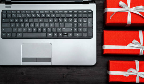 istock Top view of open laptop computer and red gift boxes on wooden table, copy space. Flat lay. Online shopping, winter holidays sales. Presents for Valentines day, March 8 (Women's Day), Mother's day 1292568253
