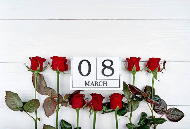 istock Beautiful red roses with cube calendar on white wooden background, copy space for text. Save the date white block calendar for International Women's Day, March 8. Greeting card. Top view, flat lay 1292568271
