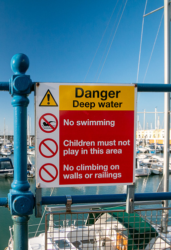 Warning Sign in Brighton Marina, England, warning that there is deep water and advising against swimming, children playing or climbing the walls or the railings