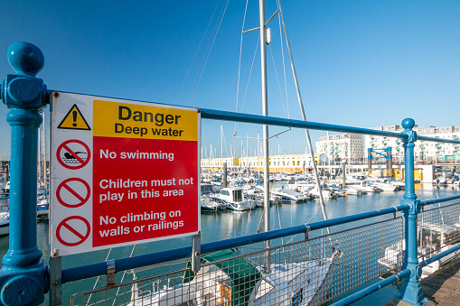 Warning Sign in Brighton Marina, England, warning that there is deep water and advising against swimming, children playing or climbing the walls or the railings