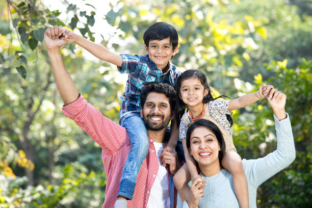 istock Mother with father carrying son on shoulder at park 1292572934