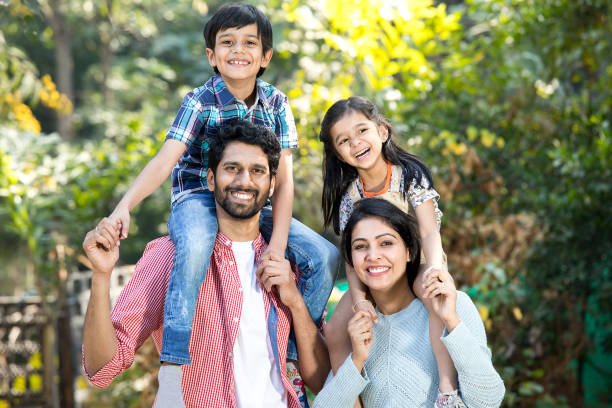 Mother with father carrying son on shoulder at park Happy mother and father carrying their kids on shoulder at park happy indian young family couple stock pictures, royalty-free photos & images