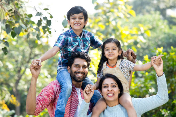 istock Mother with father carrying son on shoulder at park 1292574000