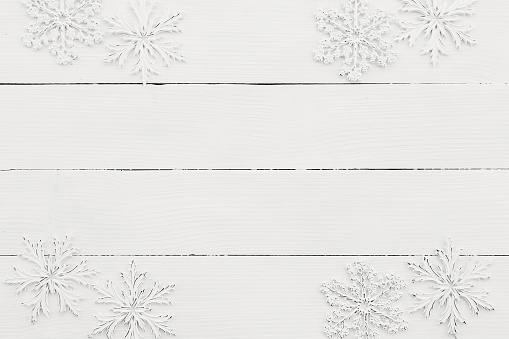 Wallpaper with white snowflakes on white wooden background. High quality photo