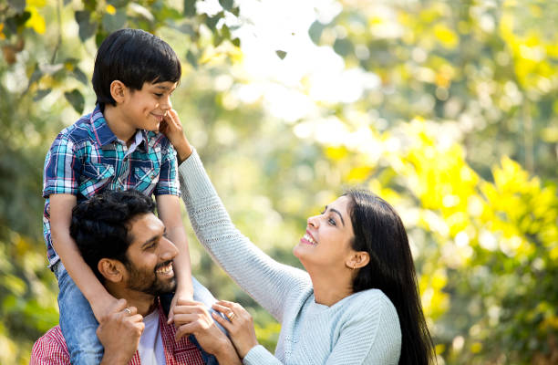 istock Mother with father carrying son on shoulder at park 1292575511