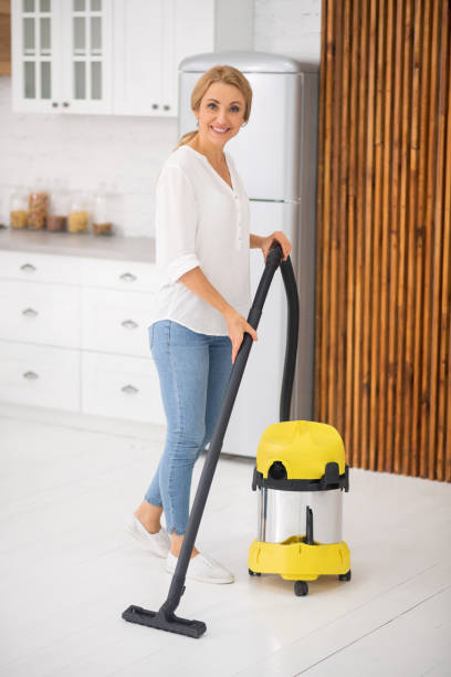 istock Woman with vacuum cleaner standing in kitchen 1292575882