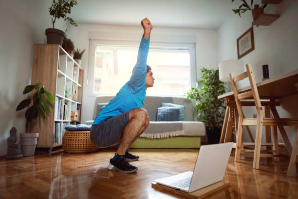istock Young man exercising overhead squats using resistance band at home 1292577169