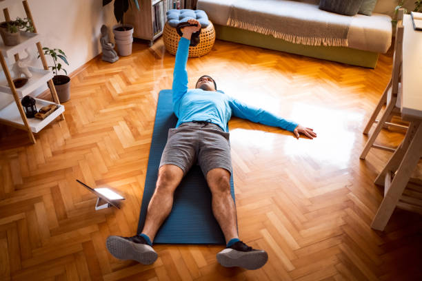 istock Young man exercising turkish get-up with a kettlebell, online workout on tablet 1292577187