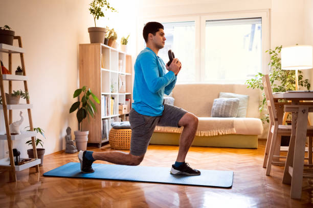 istock Young man working out split squats with kettlebell at home 1292577189