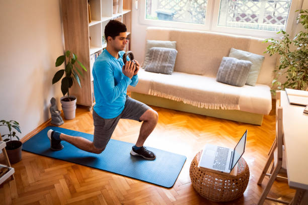 istock Young man working out with kettlebell, online workout on laptop 1292577191