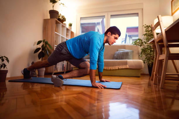 istock Young man doing cross mountain climbers at home 1292577212