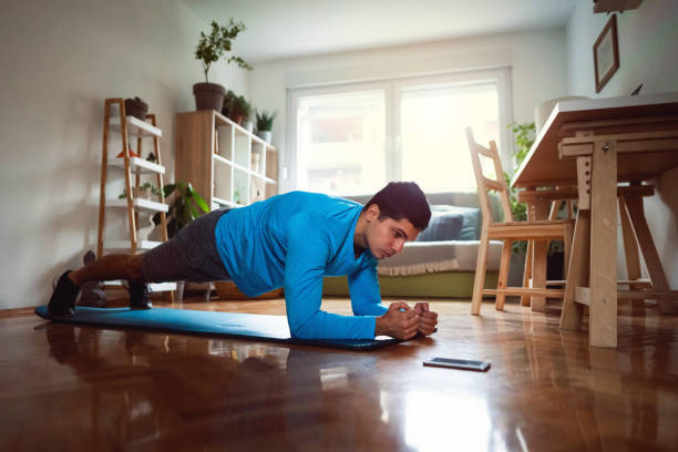 istock Young man in plank position looking at smartphone at home 1292577215
