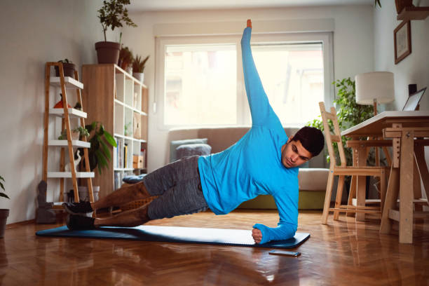 istock Young man in side plank position looking at smartphone at home 1292577218