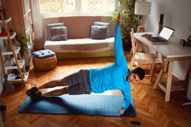 istock Young man in side plank position looking at smartphone at home 1292577219