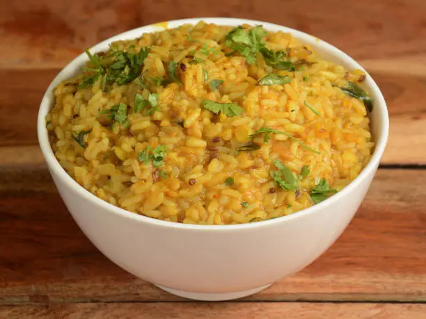 Dal khichdi or Khichadi, Tasty Indian recipe served in bowl over rustic wooden background, The food made of dal and rice combined with whole spices, onions, garlic and tomatoes etc. Selective focus