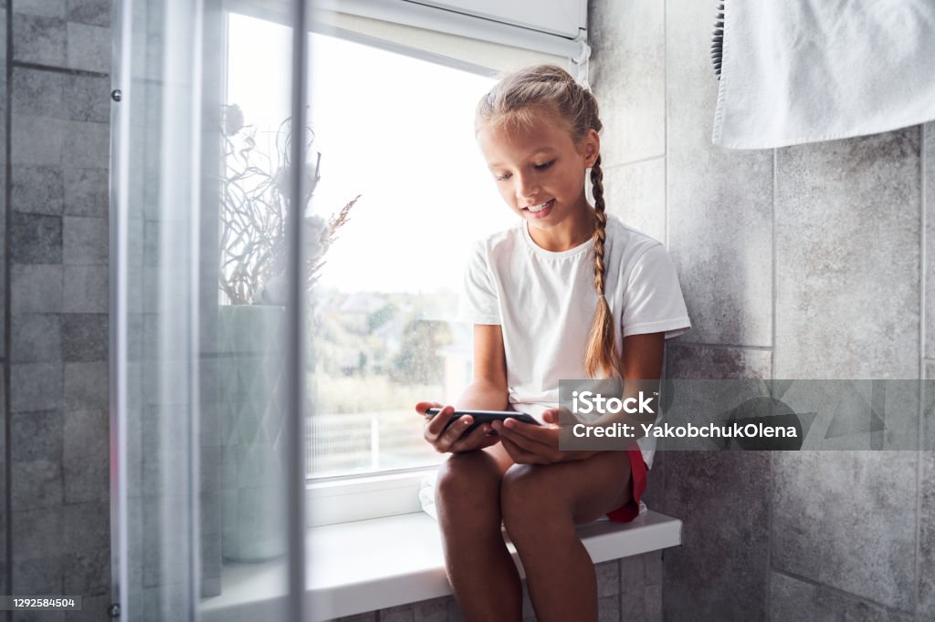 Girl Watching Funny Videos On Her Smartphone Stock Photo - Download Image  Now - Domestic Bathroom, Girls, Smart Phone - iStock