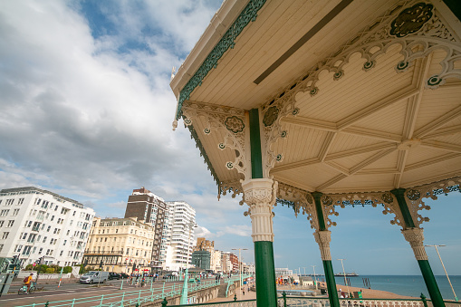 Brighton Bandstand in East Sussex, England, with hotels and apartment blocks in the background. People can be seen on the street.