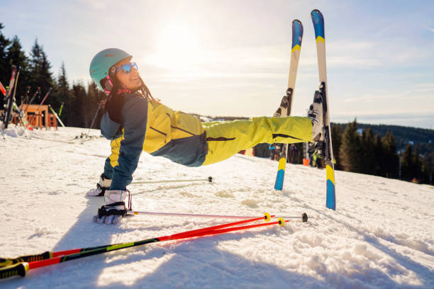 Happy female skier enjoying while relaxing on snow on a mountain and looking at camera. Copy space.