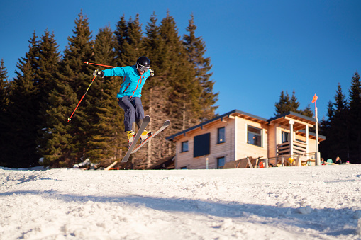 Unrecognizable male skier performing ski jump at the ski slope.
