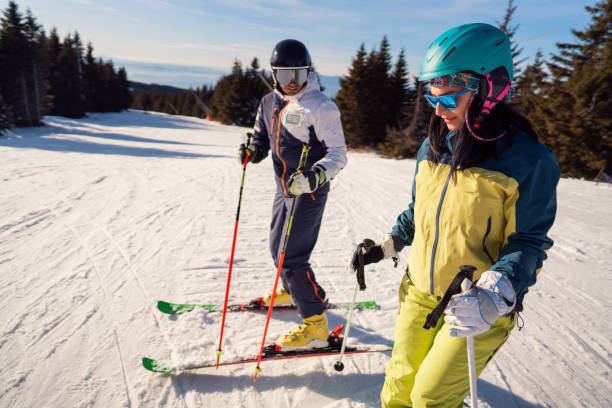 Couple of skiers at a ski slope on a sunny winter day Ski instructor teaching young woman a basics of  skiing at a ski slope on the sunny mountain. ski instructor stock pictures, royalty-free photos & images