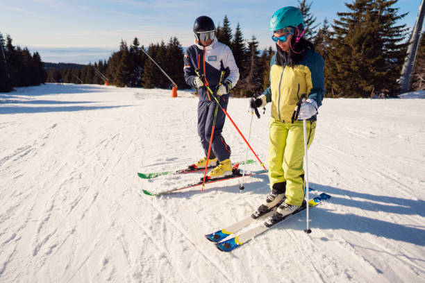 istock Ski instructor teaching young woman how to ski 1292592419