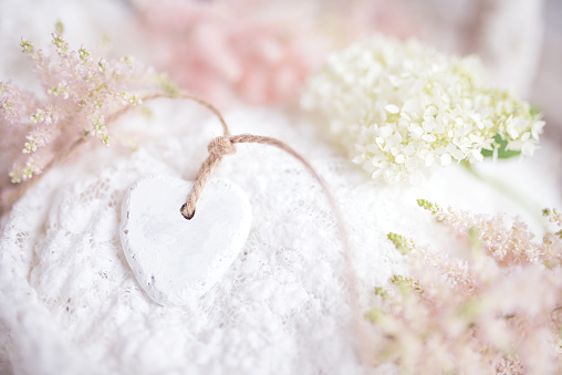 Abstract bright spring background with a heart. Blurred delicate spring blossoms for a wedding background. Horizontal close-up with short depth of field and space for text.