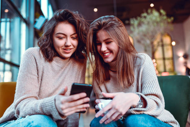 istock Smiling Females Using Smartphone While Drinking Coffee Together 1292597377